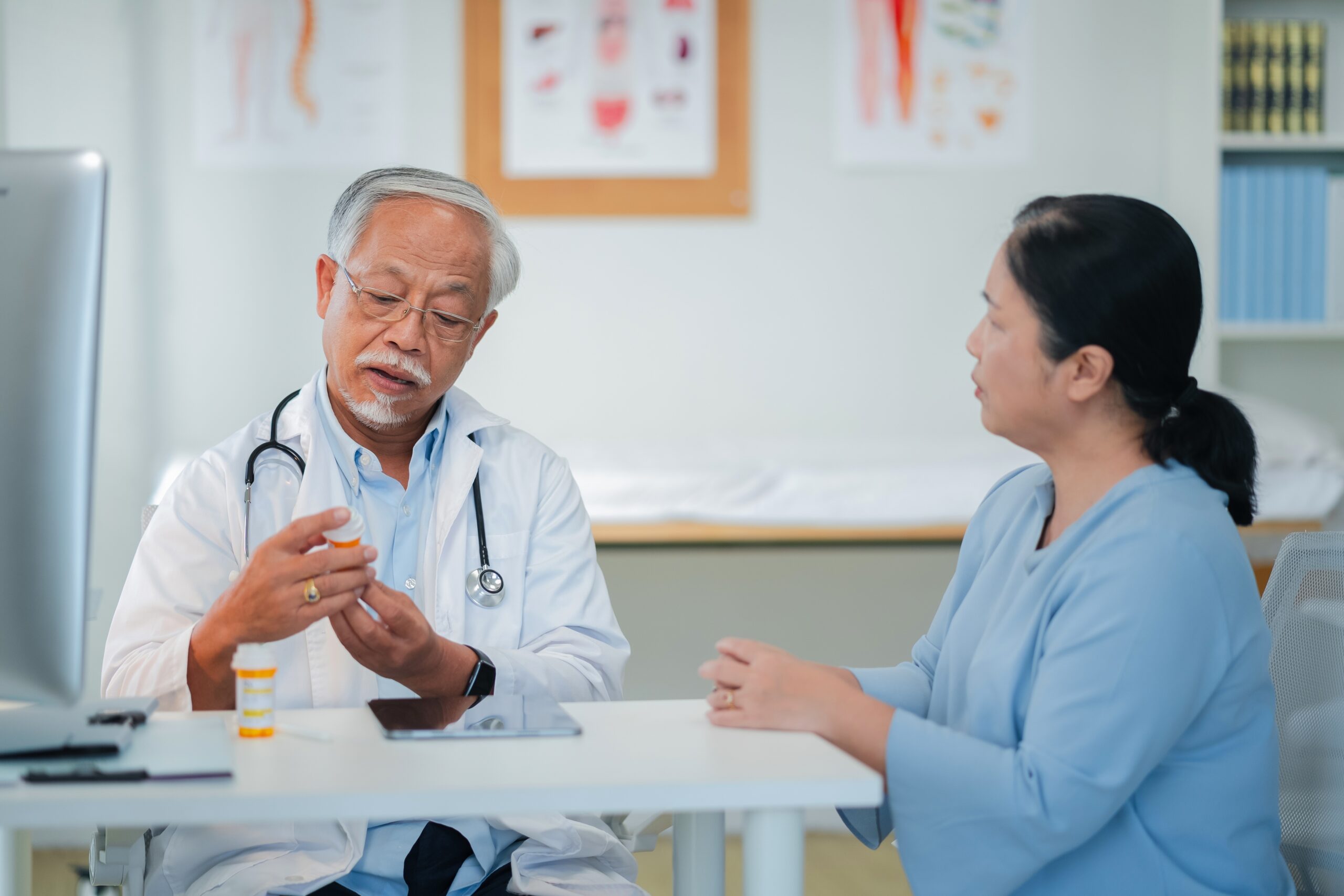 Male senior doctor discusses personalized medicine treatment with female patient hospital.