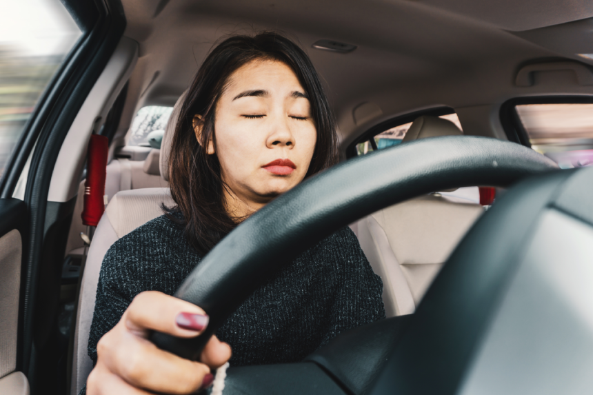 Tired Asian woman fall sleeping while driving the car