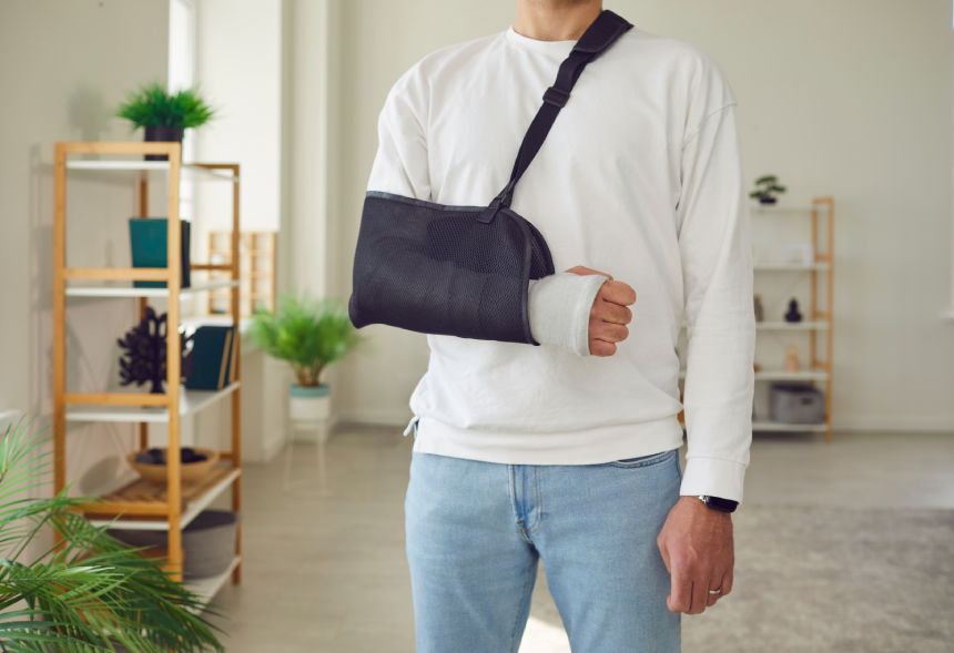 Man bravely standing despite a broken arm with fracture in the bone encased in a protective cast bandage.