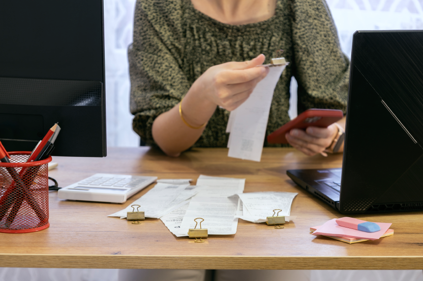 Woman holding receipts and phone, checking her expenses, income. Tax time payments