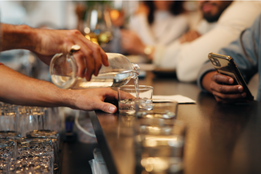 Nightclub, pub and bartender pour drinks, beverage and liquid for serving people at bar in happy hour