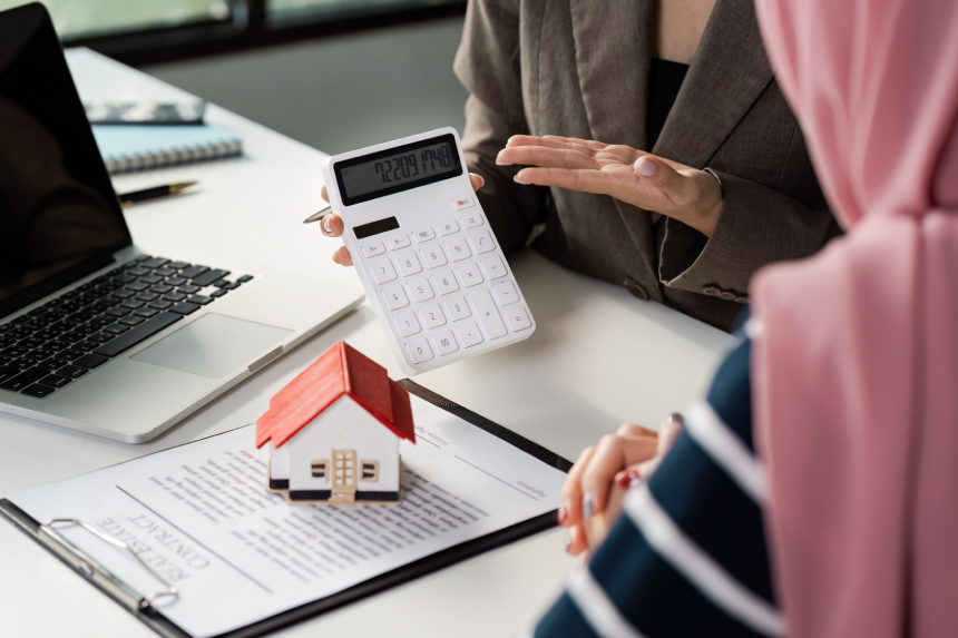 Real estate agent advising a client on property investment using a calculator and model house