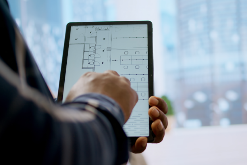 Financier realtor and client examining blueprints on a tablet and establishing the renovation plans before reaching an agreement.