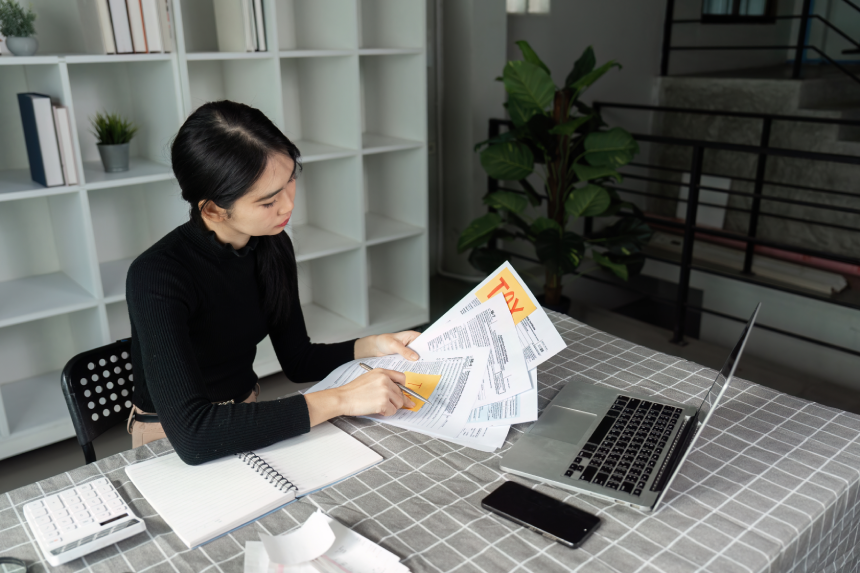 Tax management. A person reviewing tax documents at a modern workspace.