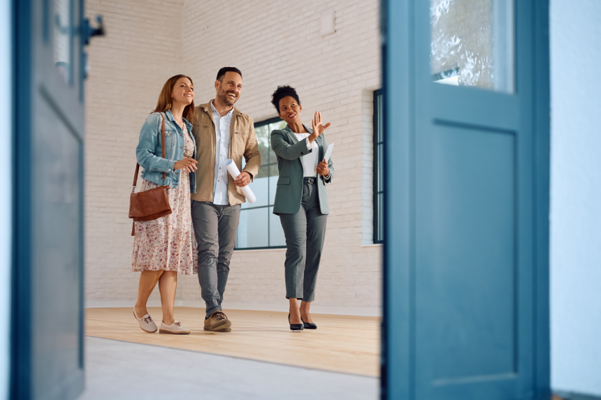 Happy African American real estate agent showing a house for sale to a couple interested in buying it