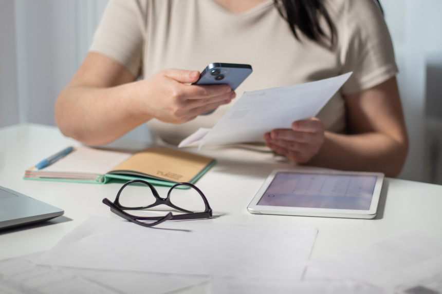 Woman paying bills online using smartphone at home. Bill paying concept.
