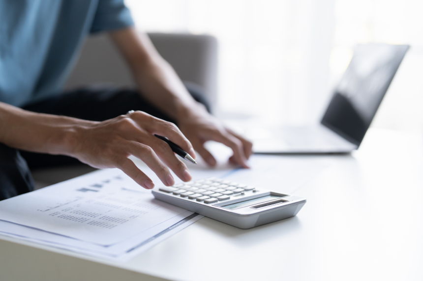 Man Managing Personal Finances Budget Household Expenses and Calculating Taxes with Calculator on the Table at Home