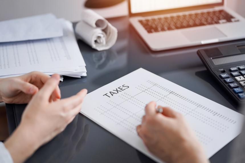 Woman accountant using a calculator and laptop computer while counting taxes for a client. Business audit and finance concepts