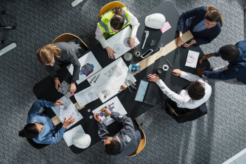 Top Down View of Diverse Team of Real Estate Construction Engineers Discussing Blueprints, Documents in Corporate Office.