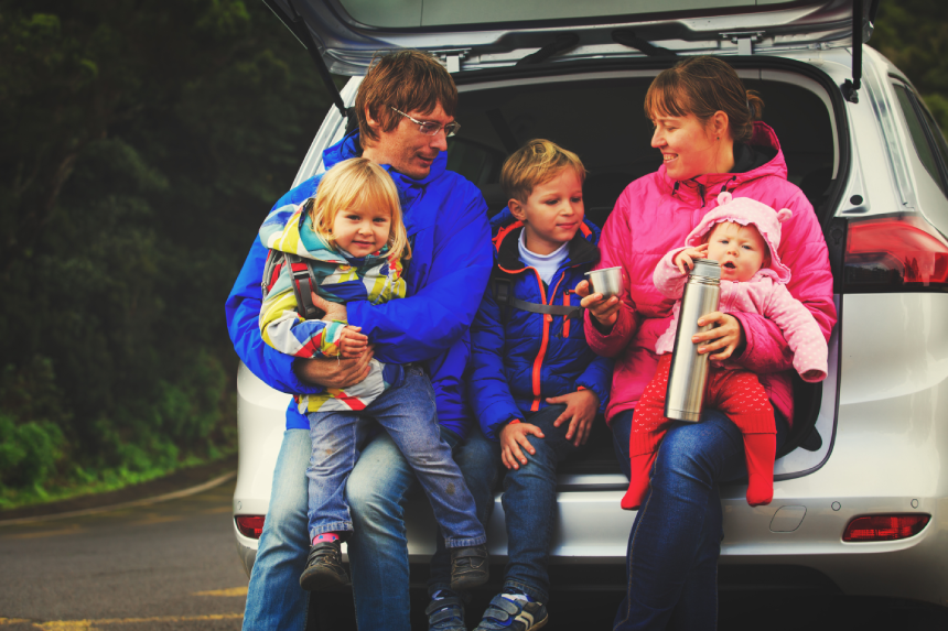 happy family with tree kids travel by car on road