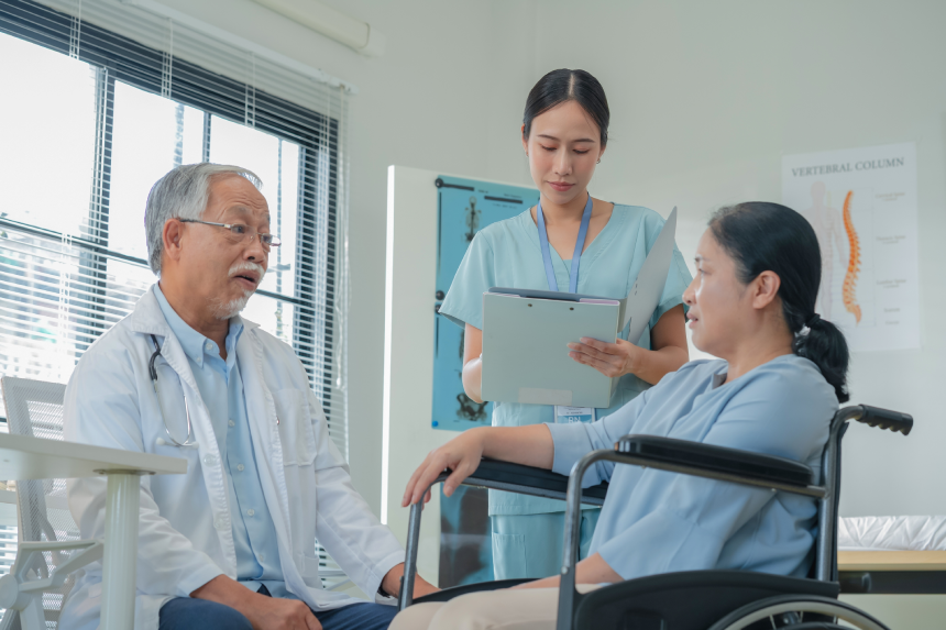 Asian healthcare providers deliver patient-centered consultation to senior woman, explaining medical condition through health literacy communication and holistic care approach for optimal wellness
