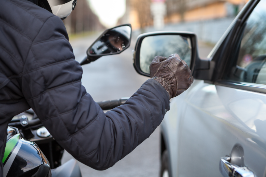 Motorcyclist knocking on the car window with a glove