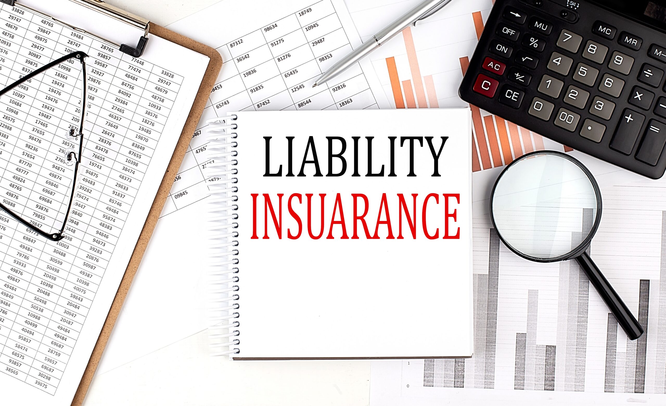 LIABILITY INSURANCE text on notebook with clipboard and calculator on chart background