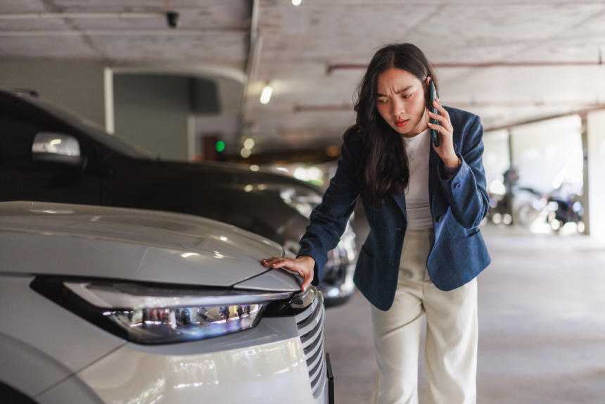 Woman feeling stressed calling for help after vehicle accident in an underground parking lot