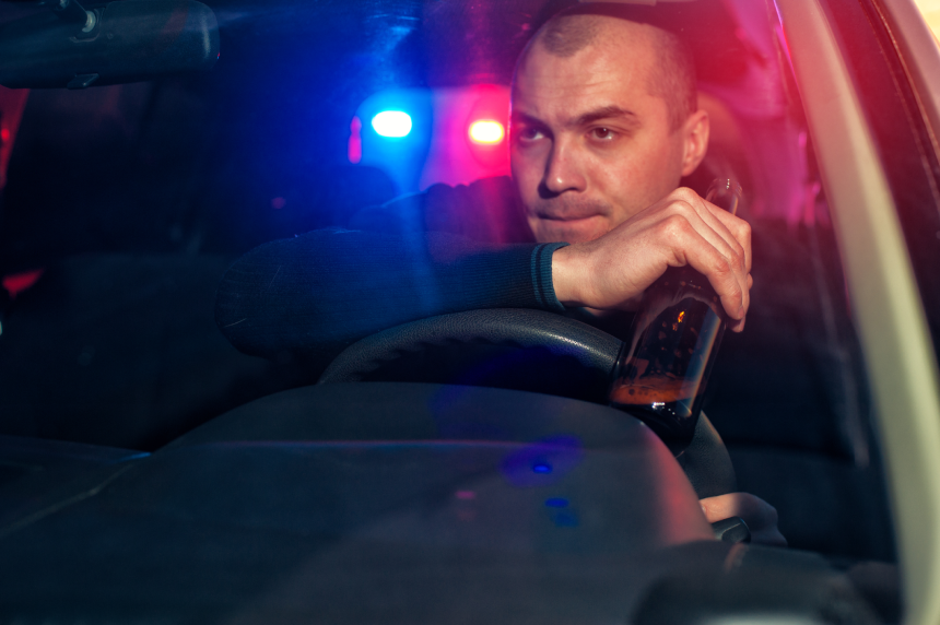Young drunk man with beer bottle chased by police. Driving under alcohol influence.