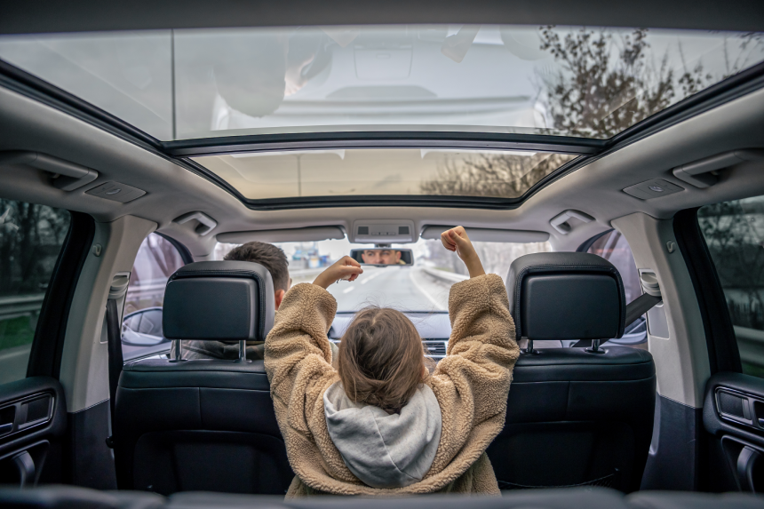 Rear view. Little girl sitting in back seat of car during family trip.