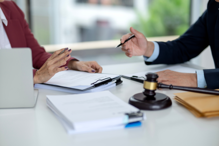 Adult Asian hands review legal paperwork contract terms discuss justice issues with attorney client in professional office environment