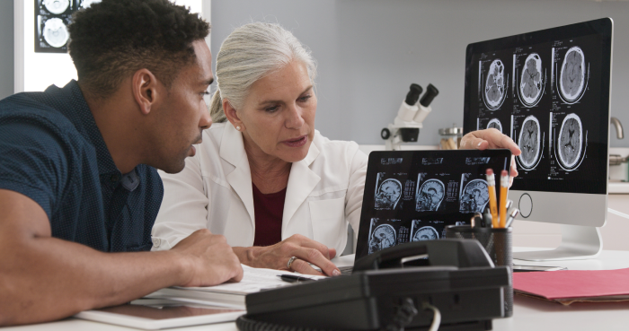 Millennial black patient consulting with senior doctor about concussion
