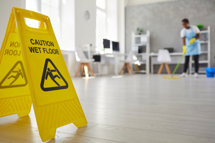 Close up plastic caution sign with figure that slips and falls warning us of wet slippery office floor.