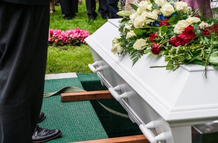 Mourners standing beside coffin near grave