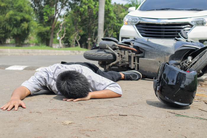 Motorcycle Accident Scene With Man Injured and Lying on Road
